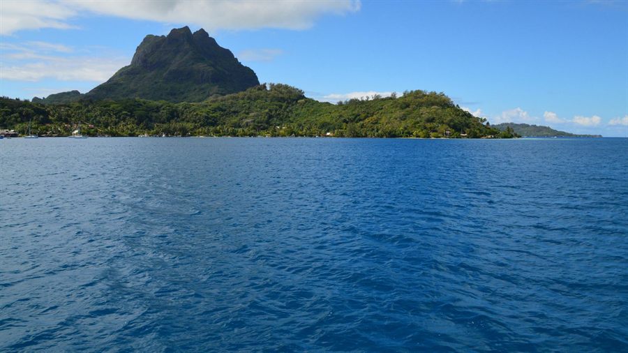 Lush island and mountain peak rising from a blue South Pacific sea