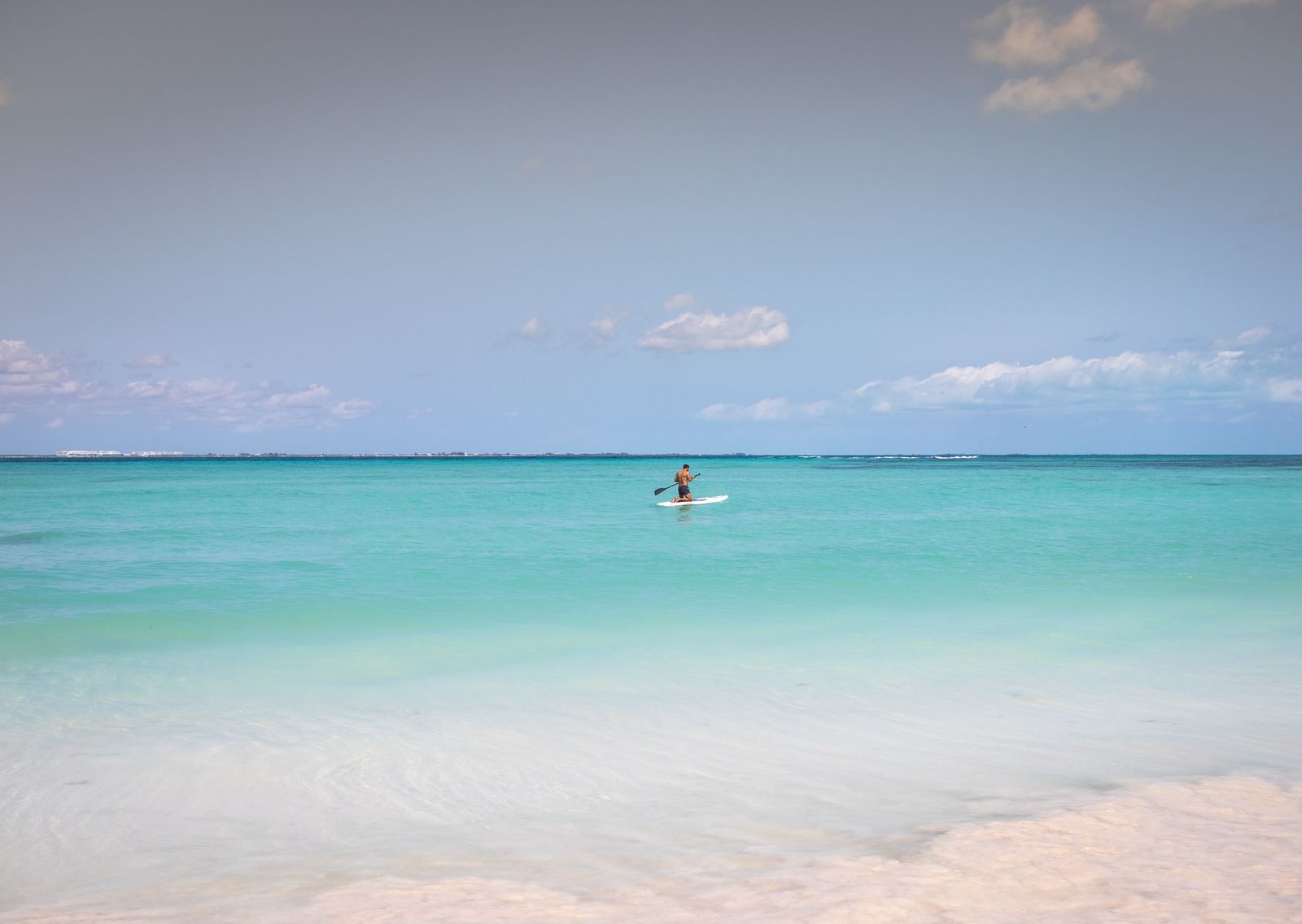 Paddleboarder on turquoise Caribbean water off Canc&uacute;n, Mexico, a favorite answer to where to cruise in December