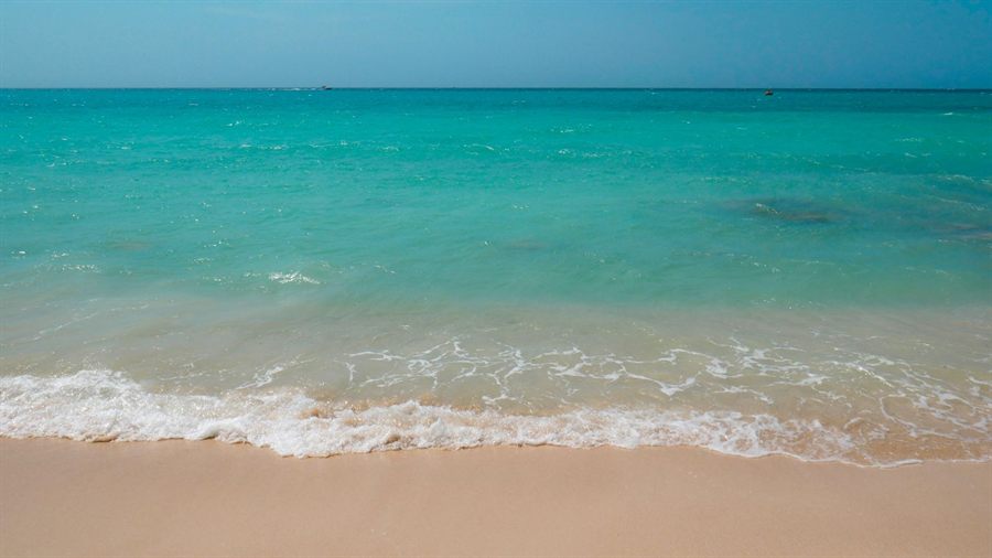 Gentle surf on a sandy beach with clear turquoise water