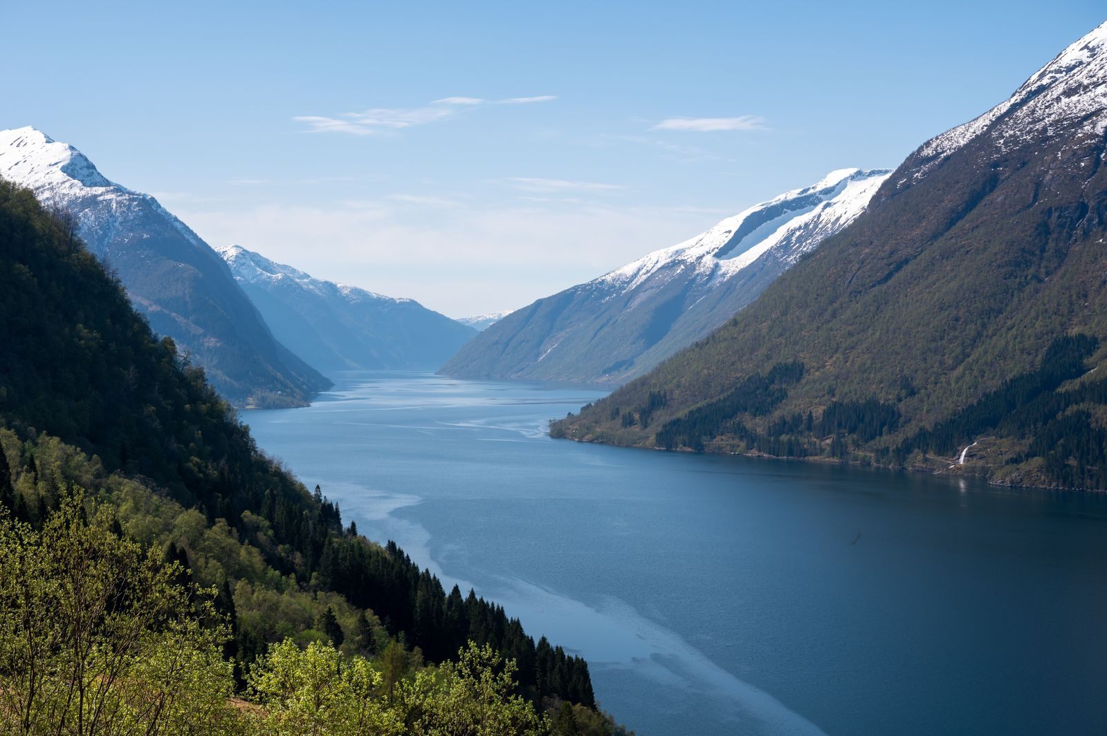 Snow-capped mountains above a deep blue fjord, the kind of scenery that makes Norway a summer cruise destination